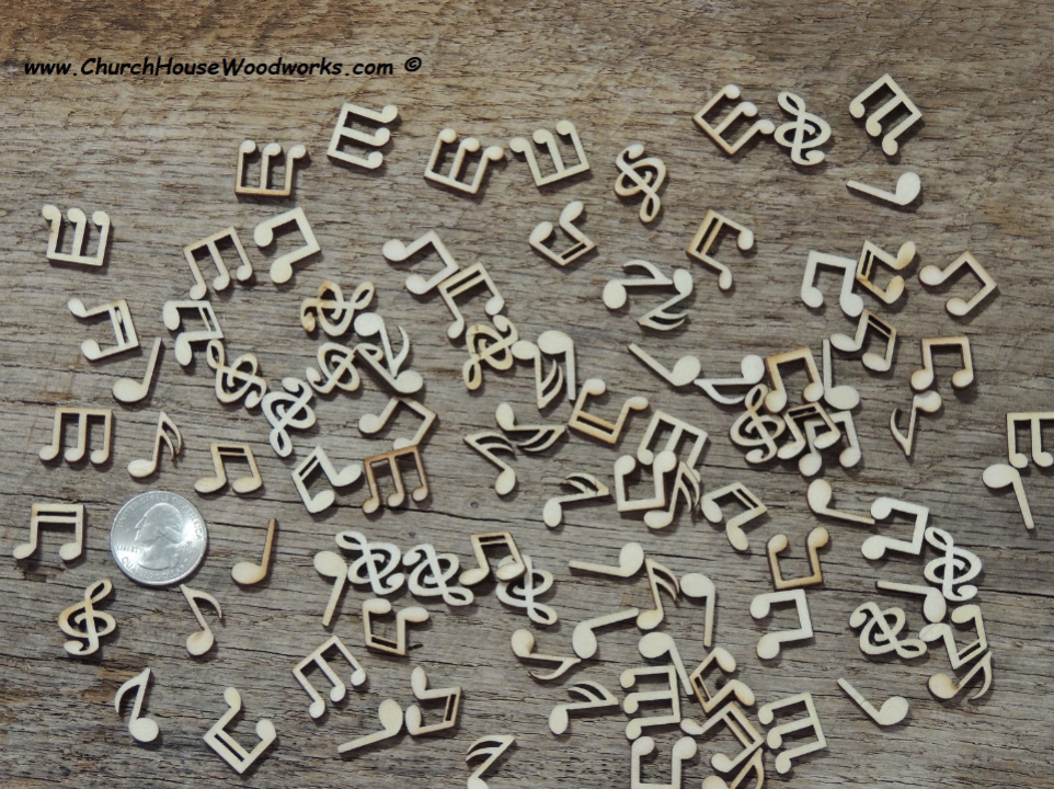 A close-up photo of 100 small wooden music note shapes, including whole notes, eighth notes, sixteenth notes, and treble clefs, displayed next to a quarter for size reference. The shapes are made of light, unfinished wood with smooth surfaces.